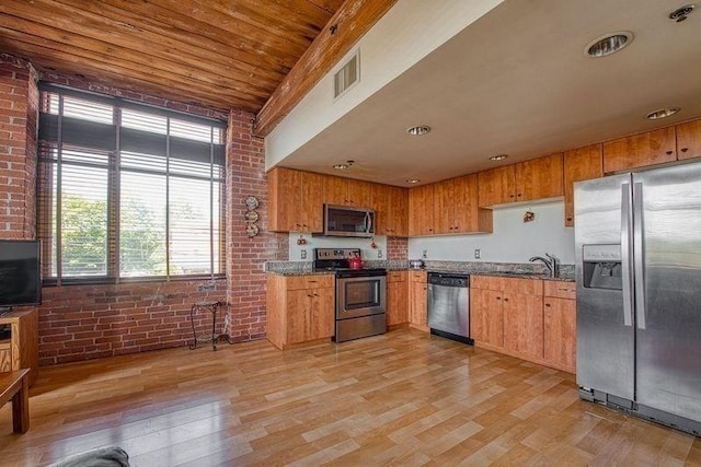147 Centre St Unit 201, Brockton, MA 02302 - kitchen with stainless steel appliances, brick wall, a sink, light wood-style flooring, and dark stone counters