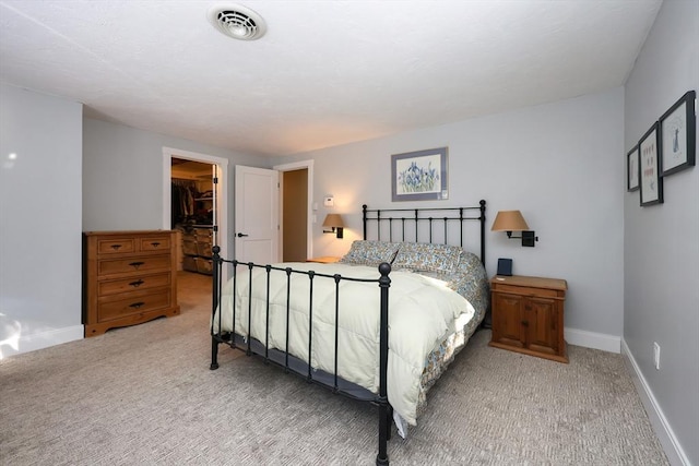 bedroom featuring a walk in closet, light colored carpet, and a closet