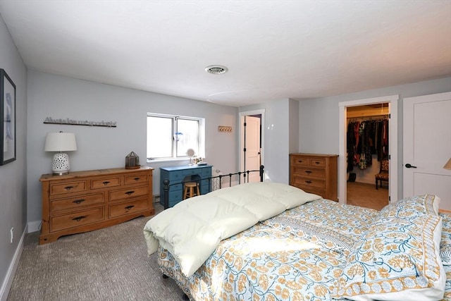 bedroom with a walk in closet, light colored carpet, and a closet