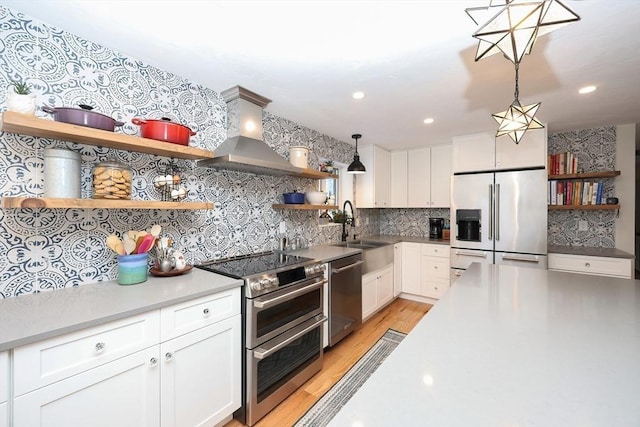 kitchen featuring hanging light fixtures, exhaust hood, white cabinets, and appliances with stainless steel finishes