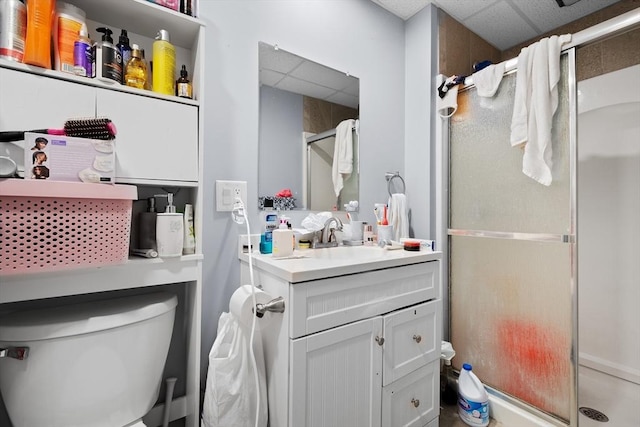 bathroom featuring a shower with shower door, vanity, a paneled ceiling, and toilet