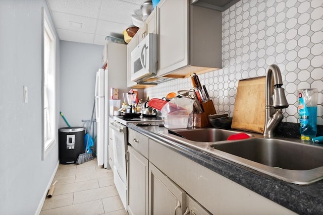 kitchen featuring a paneled ceiling, sink, white appliances, and light tile patterned flooring