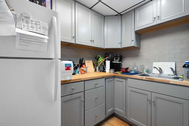 kitchen with white fridge, wood counters, tasteful backsplash, and gray cabinets