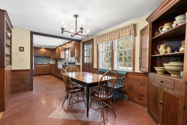 dining room with wood walls, a notable chandelier, and a wainscoted wall