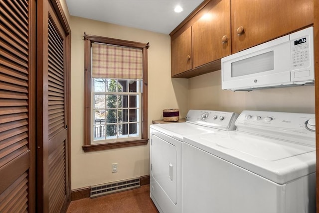 washroom with baseboards, cabinet space, visible vents, and washing machine and clothes dryer