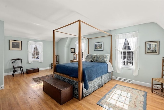 bedroom featuring baseboards, visible vents, vaulted ceiling, and wood finished floors