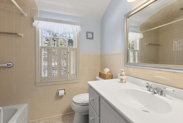 bathroom featuring toilet, a wainscoted wall, tile patterned floors, vanity, and tile walls