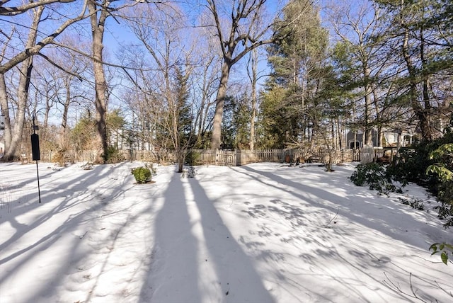 snowy yard featuring fence