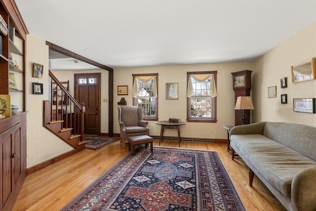 sitting room with light wood finished floors, stairway, baseboard heating, and baseboards