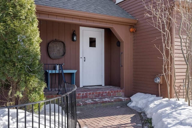 doorway to property with roof with shingles