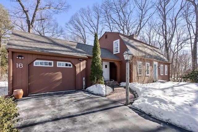 view of front facade featuring a garage, aphalt driveway, a shingled roof, and a gambrel roof