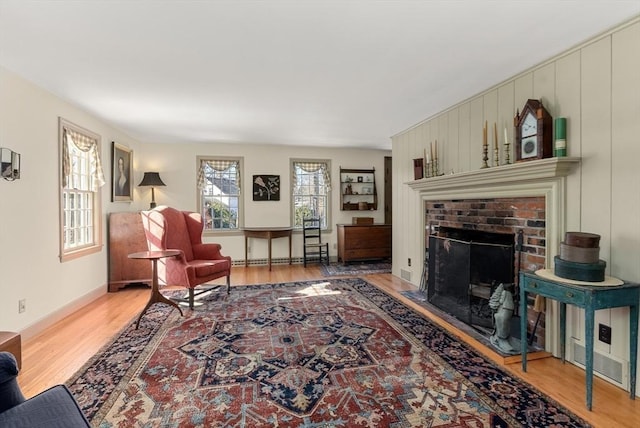 living area featuring a brick fireplace, wood finished floors, and a baseboard radiator