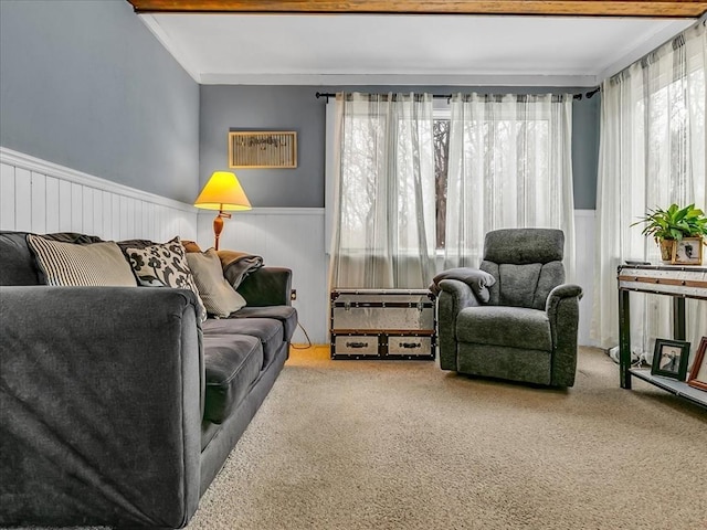 carpeted living room with beamed ceiling and wainscoting