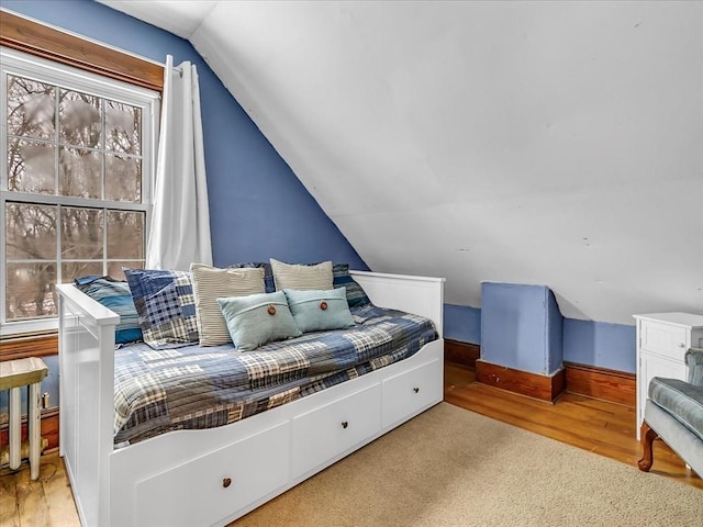 bedroom with vaulted ceiling and wood finished floors