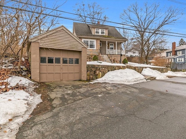 view of front of house with covered porch, a garage, driveway, roof with shingles, and a chimney