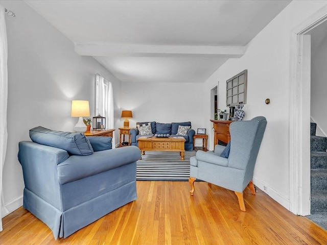 living room with stairs, beamed ceiling, wood finished floors, and baseboards