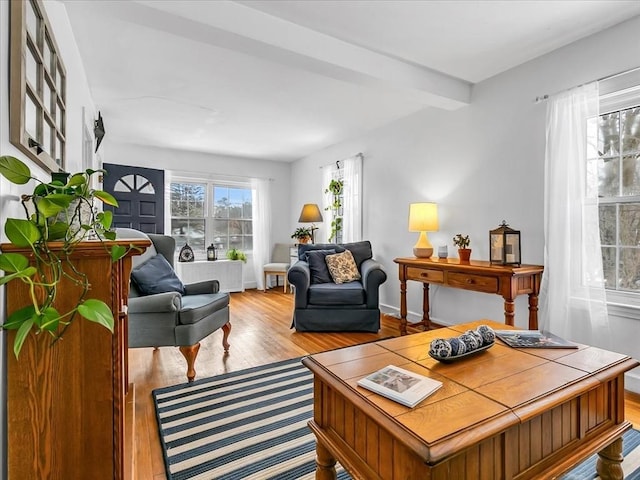 living area featuring beamed ceiling, wood finished floors, and baseboards