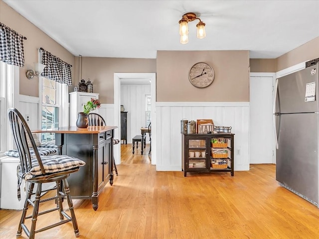 dining room with light wood-type flooring and wainscoting