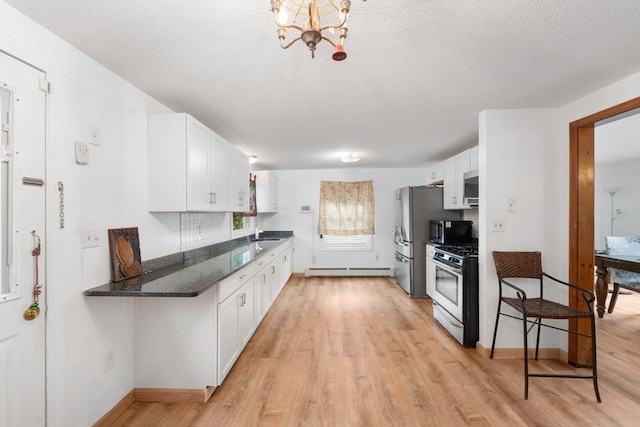 kitchen with dark stone counters, a baseboard radiator, a notable chandelier, white cabinetry, and stainless steel appliances