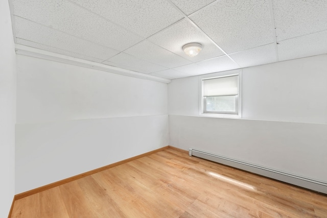 spare room with hardwood / wood-style flooring, a drop ceiling, and a baseboard radiator