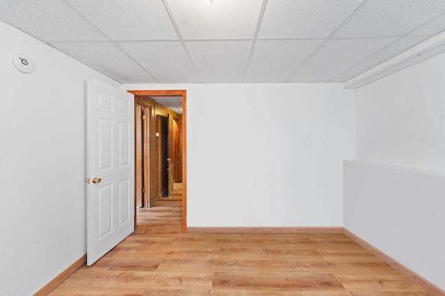 unfurnished room with a paneled ceiling and light wood-type flooring