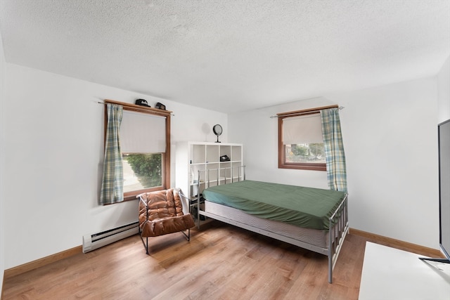 bedroom featuring a textured ceiling, light hardwood / wood-style flooring, and baseboard heating