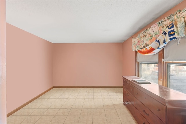 empty room with light tile patterned flooring and a textured ceiling