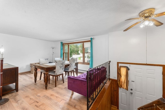 dining room featuring a textured ceiling, light wood-type flooring, ceiling fan, and a baseboard heating unit