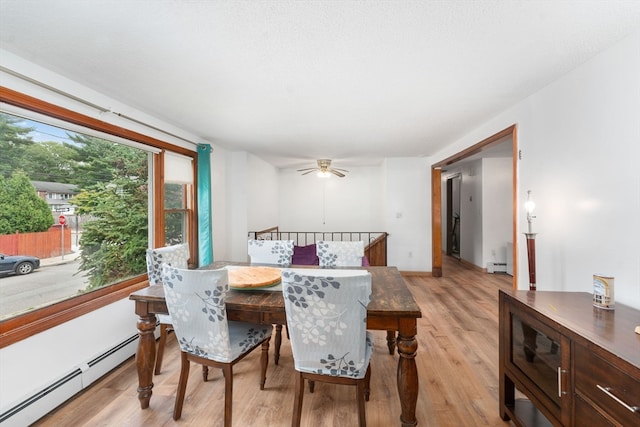 dining room with ceiling fan, light hardwood / wood-style floors, and a baseboard heating unit