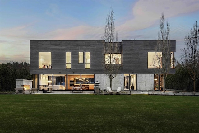 back of house at dusk with a patio, an outdoor living space, and a lawn