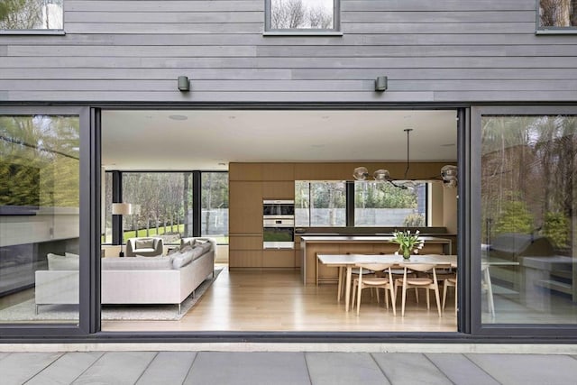 doorway to outside featuring healthy amount of natural light, a chandelier, and wooden walls