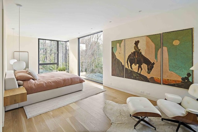 bedroom featuring access to exterior, wood finished floors, and floor to ceiling windows
