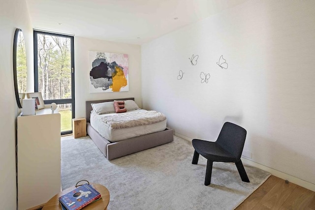 bedroom featuring wood finished floors and floor to ceiling windows
