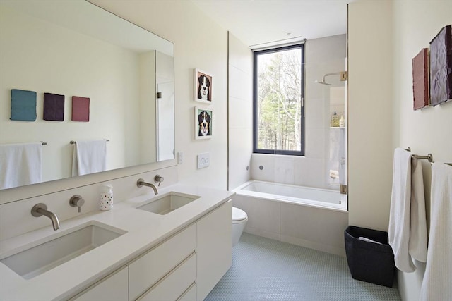 bathroom featuring toilet, tiled shower / bath combo, and double vanity