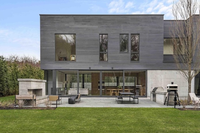 rear view of property with exterior fireplace, a patio area, and a yard