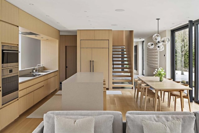 kitchen featuring light wood-style flooring, light brown cabinets, light countertops, decorative light fixtures, and a chandelier