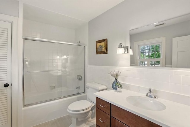 171 Brentwood Cir, North Andover, MA 01845 - bathroom featuring vanity, bath / shower combo with glass door, toilet, and tile walls