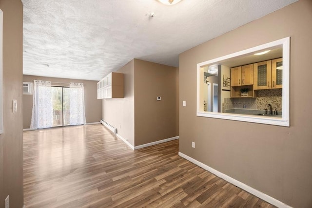 spare room with baseboard heating, sink, wood-type flooring, and a textured ceiling