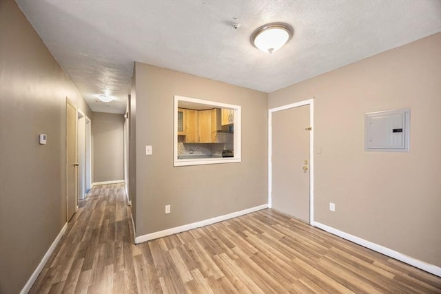 unfurnished room featuring light wood-type flooring, a textured ceiling, and electric panel