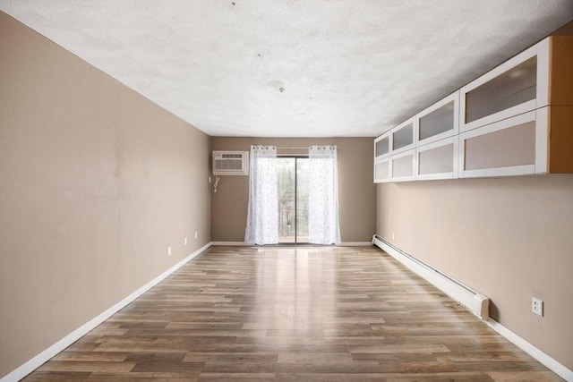 spare room with hardwood / wood-style floors, a wall mounted AC, and a baseboard radiator