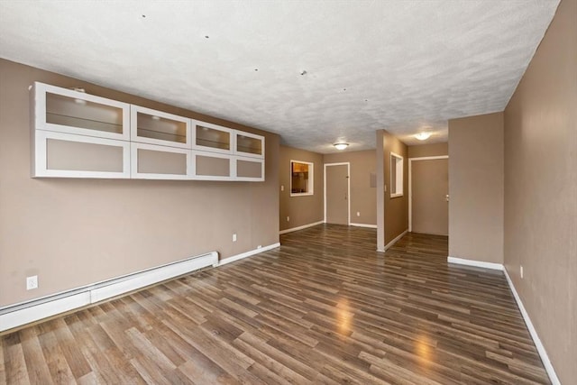 spare room featuring dark wood-type flooring and a baseboard heating unit