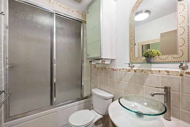 full bathroom with toilet, sink, tile walls, and combined bath / shower with glass door