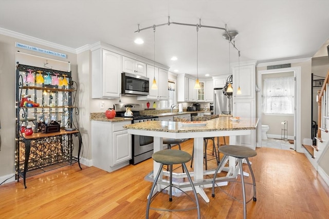 16 Ocean St Unit A, Salisbury, MA 01952 - kitchen featuring stainless steel appliances, white cabinetry, crown molding, a kitchen bar, and light stone countertops