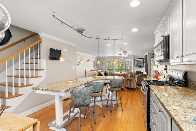 16 Ocean St Unit A, Salisbury, MA 01952 - kitchen with stainless steel appliances, light wood-style floors, ceiling fan, white cabinetry, and crown molding