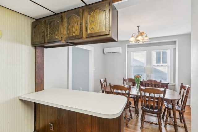 45 Franklin Ave, Quincy, MA 02170 - kitchen featuring a peninsula, a chandelier, an AC wall unit, light countertops, and light wood-style floors