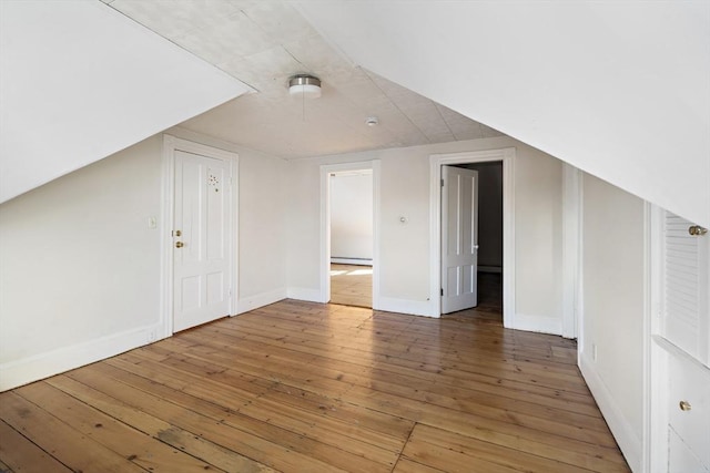 additional living space featuring hardwood / wood-style flooring, a baseboard radiator, and lofted ceiling