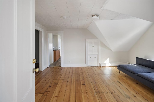 additional living space featuring lofted ceiling and light hardwood / wood-style floors