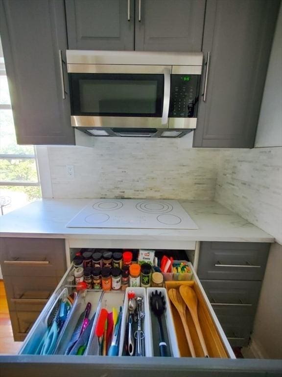 kitchen featuring gray cabinets, decorative backsplash, and white electric cooktop