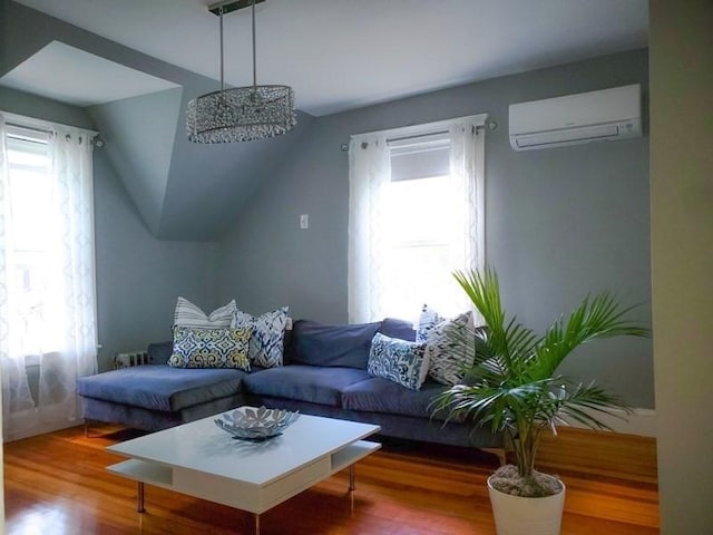 living room with a healthy amount of sunlight, a wall mounted air conditioner, and hardwood / wood-style flooring