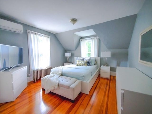 bedroom featuring a wall unit AC, radiator, hardwood / wood-style floors, and multiple windows